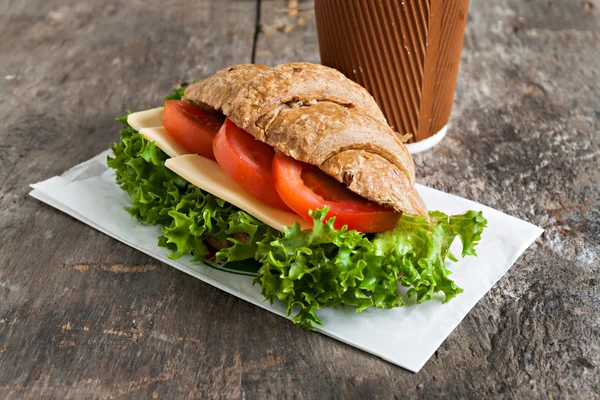 Grain vegetarian croissant sandwich and a paper cup of coffee on — Stock Photo, Image