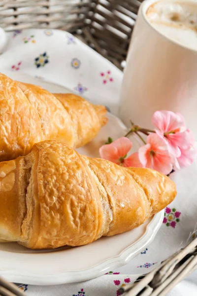 Croissants, Kaffeetasse, Blume im romantischen Stil auf einem Weidenkorb — Stockfoto