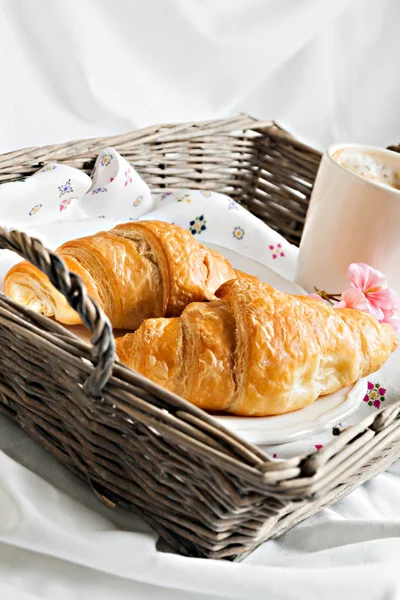 Croissants, Kaffeetasse, Blume im romantischen Stil auf einem Weidenkorb — Stockfoto