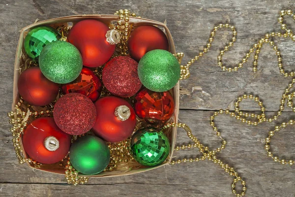 Rode kerstballen, goud, groen, kralen liggen in een houten mand t — Stockfoto