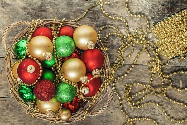 Χριστούγεννα μπάλες κόκκινο, χρυσό, πράσινο, χάντρες βρίσκονται σε ένα ξύλινο καλάθι τ — Φωτογραφία Αρχείου
