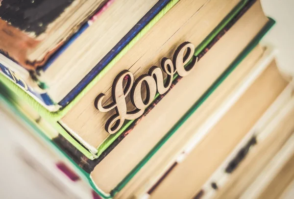 On a stack of old books wooden word love — Stock Photo, Image