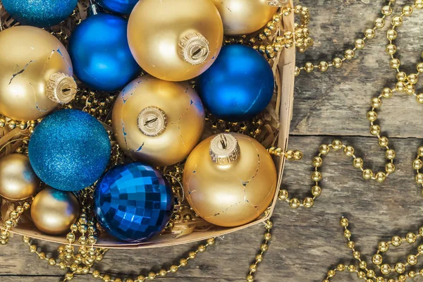 Blå julgranskulor och guld, pärlor ligga i en trä korg topp — Stockfoto