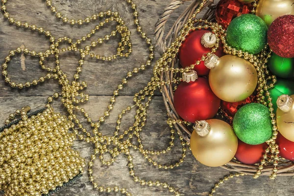 Χριστούγεννα μπάλες κόκκινο, χρυσό, πράσινο, χάντρες βρίσκονται σε ένα ξύλινο καλάθι τ — Φωτογραφία Αρχείου