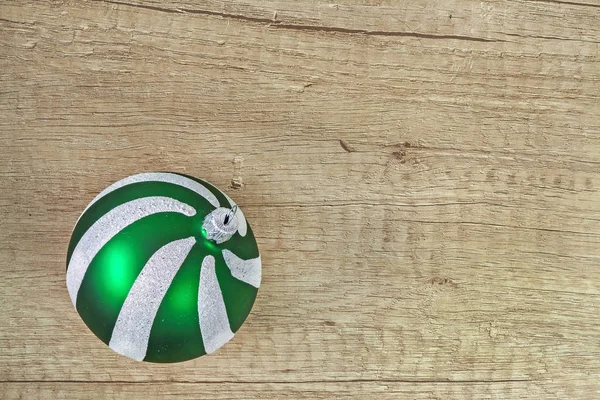 Bola de Navidad de cristal verde sobre un fondo de madera claro — Foto de Stock