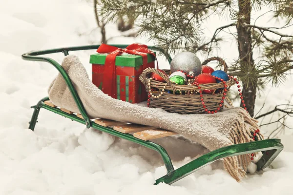 Traîneaux, couverture, panier avec jouets et coffrets cadeaux dans une neige pour — Photo