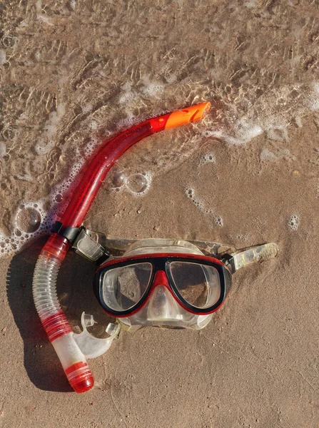 Masker en snorkel liggend op nat zand met golven — Stockfoto