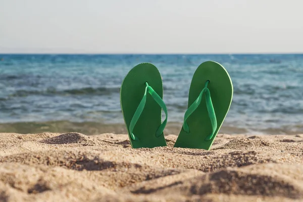 Chanclas verdes en la arena cerca del mar — Foto de Stock