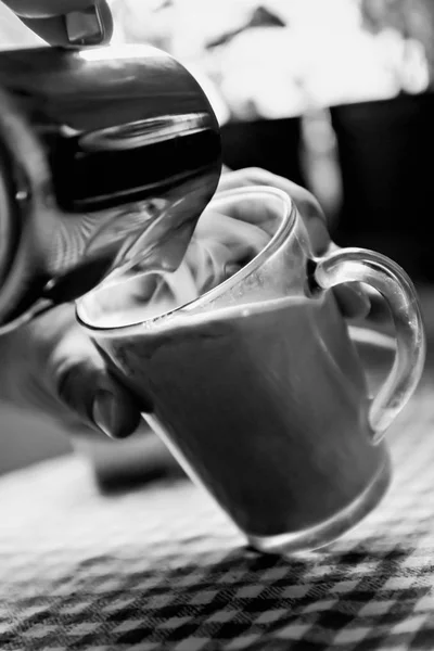 Hombre vertiendo café en una taza de leche en blanco y negro — Foto de Stock