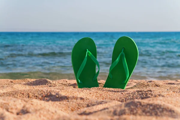 Chanclas verdes en la arena cerca del mar — Foto de Stock