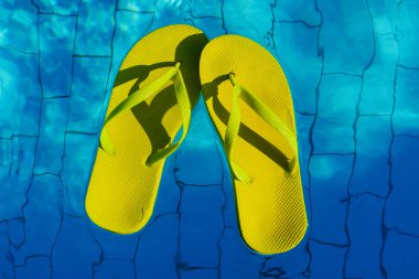 Üstten Görünüm bir yüzme havuzunda yüzen sarı parmak arası terlik