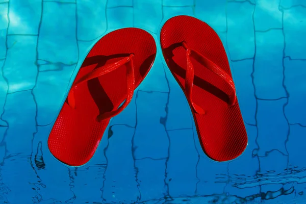 Red flip-flops floating in a swimming pool, a top view — Stock Photo, Image