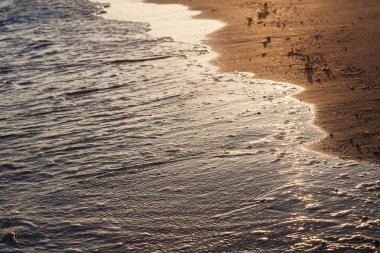 Gün batımında altın kumsalda parlak tropik deniz dalgası