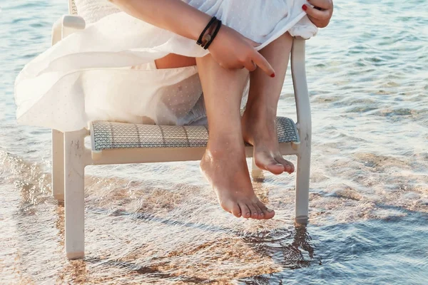 Bare legs girl in a white dress touched the sea water — Stock Photo, Image