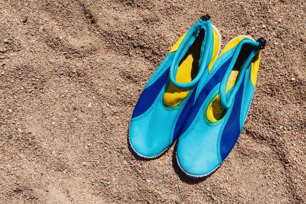 Geel-blauwe schoenen ter bescherming van de voeten van het koraal op het strand — Stockfoto
