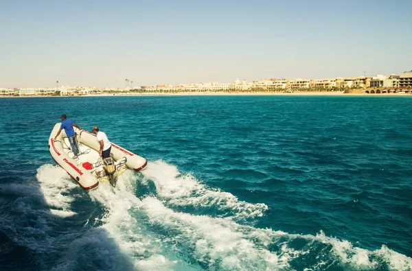 Bote a motor de goma con dos hombres a alta velocidad por mar — Foto de Stock