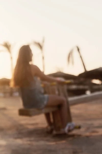 Young lady riding on a swing at sunset on a background of palm t — Stock Photo, Image