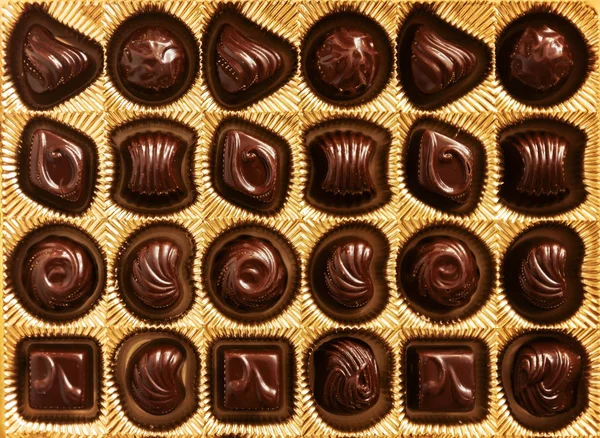 Caramelle di cioccolato di diverse forme in una scatola d'oro, vista dall'alto, s — Foto Stock