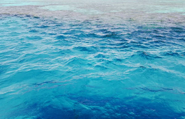 Via de blauwe zee met golven zichtbaar koraalriffen — Stockfoto