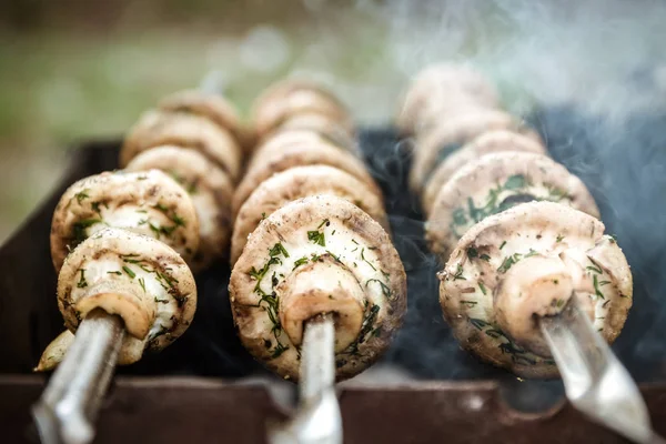 Grilled mushrooms on skewers cooked in a brazier, close-up, retr — Stock Photo, Image