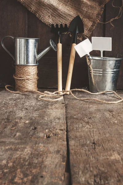 Herramienta de jardín, pala, rastrillo, regadera, cubo, bolsa en una madera — Foto de Stock