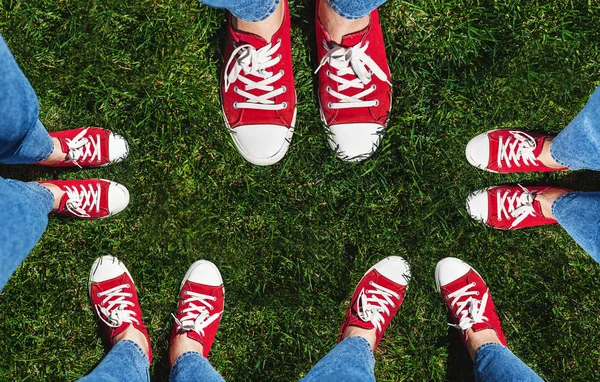 Collage of legs in old red sneakers on green grass. View from ab