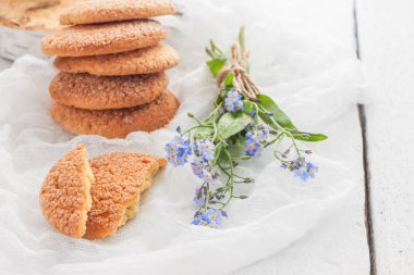 Beyaz bir masada, sandy yuvarlak kurabiye, bir kırık ve bir buket 