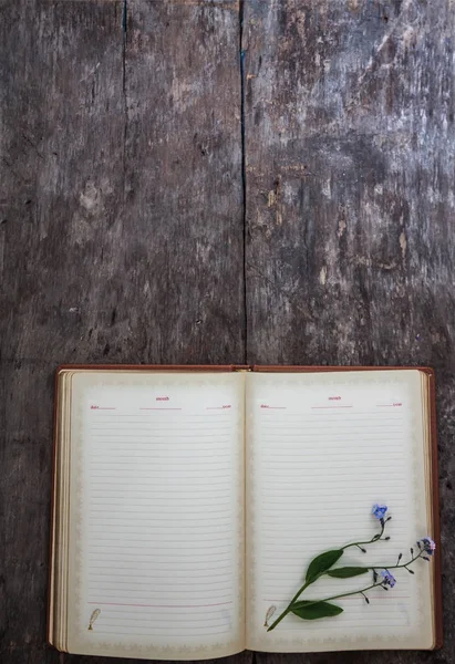 Sobre un viejo fondo de madera se encuentra un viejo cuaderno y un ramo de — Foto de Stock