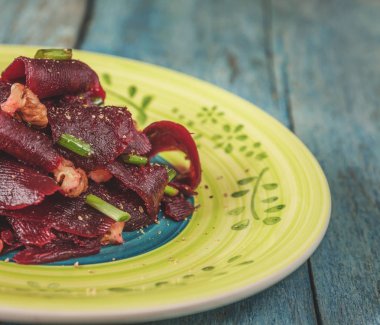 Bir vejetaryen yalın pancar salatası, yeşil üzerinde parlak bir etnik plakadır 