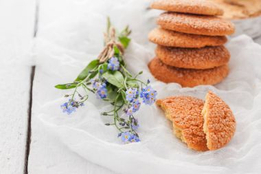 Beyaz bir masada, sandy yuvarlak kurabiye, bir kırık ve bir buket 