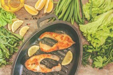 Pişmiş biftek alabalık balık dökme demir formunda, Yeşiller, çevresinde bırakır,