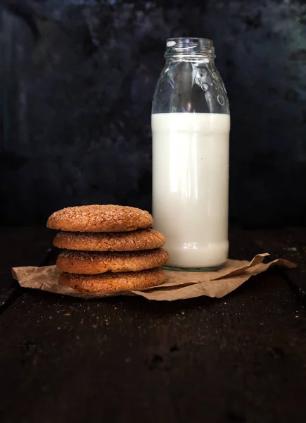 Bottle with milk and a stack of cookies on a dark background, re