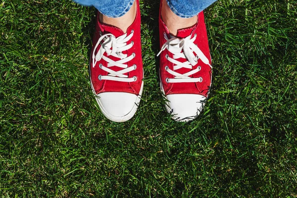 Nogi w stare czerwone trampki na zielonej trawie. Widok z góry. Emisji co — Zdjęcie stockowe