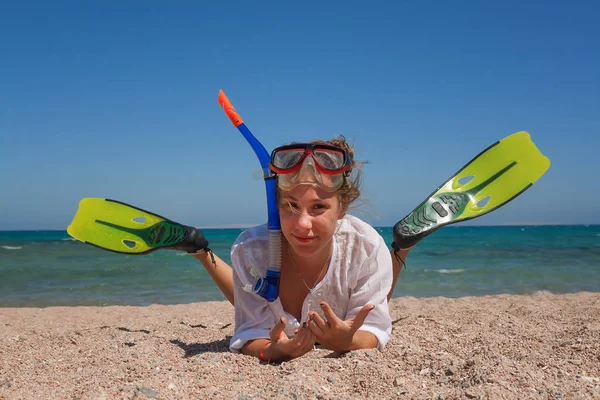 Een jonge vrouw in een masker en vinnen om te snorkelen, ligt in het san — Stockfoto