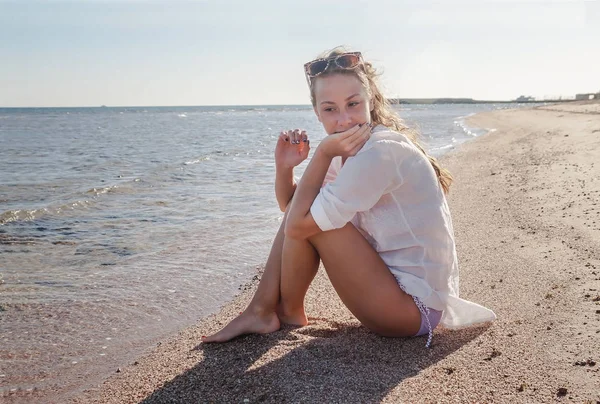Young woman with a pensive look sits on the seashore. The concep — Stock Photo, Image