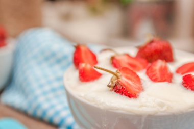 Bir fincan yoğurt ve mavi kaşık havlu üzerinde taze çilek