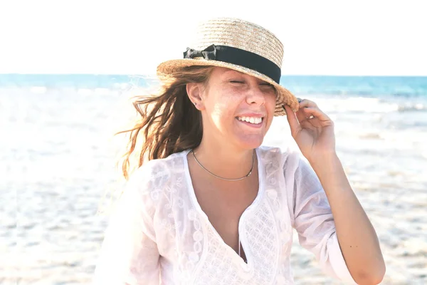 Νεαρή γυναίκα με ένα ψάθινο καπέλο, διακαώς γέλιο κατά το backg — Φωτογραφία Αρχείου