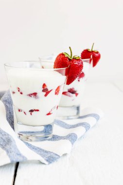 Tatlı yoğurt ve çilek katmanları bir cam üzerinde mavi bir şerit