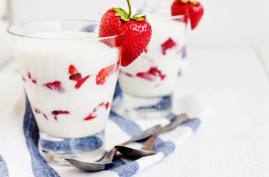 Tatlı yoğurt ve çilek katmanları bir cam üzerinde mavi bir şerit