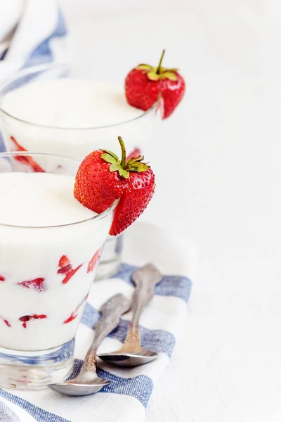 Dessert yogurt and strawberry layers in a glass on a blue stripe — Stock Photo, Image