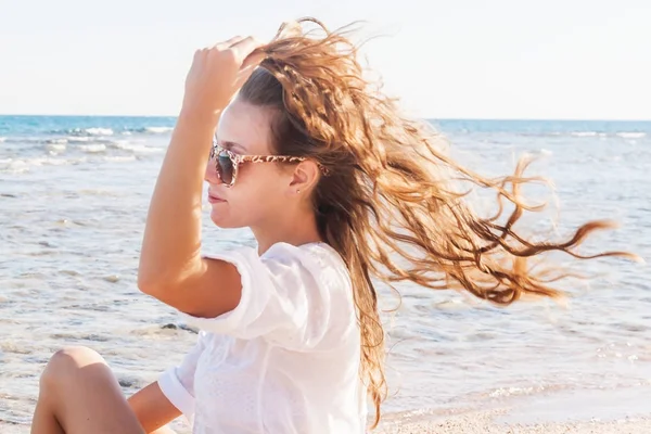 Uma jovem mulher de óculos de sol segura uma mão em seu cabelo tremulando — Fotografia de Stock