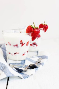 Tatlı yoğurt ve çilek katmanları bir cam üzerinde mavi bir şerit