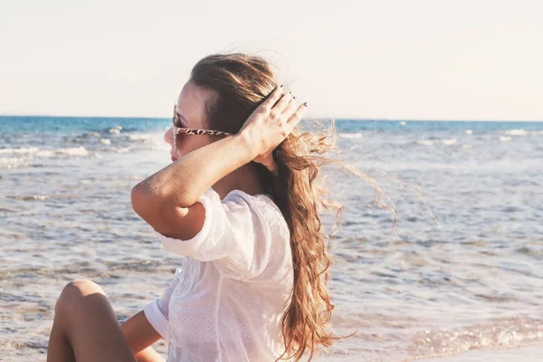 Güneş gözlüklü genç bir kadın onun saç çırpınan bir el tutar 