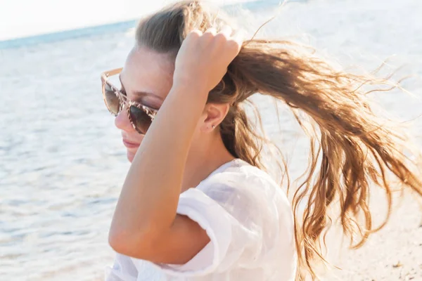 Una joven con gafas de sol sostiene una mano sobre su cabello revoloteando —  Fotos de Stock