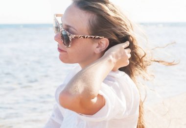 Güneş gözlüklü genç bir kadın onun saç çırpınan bir el tutar 