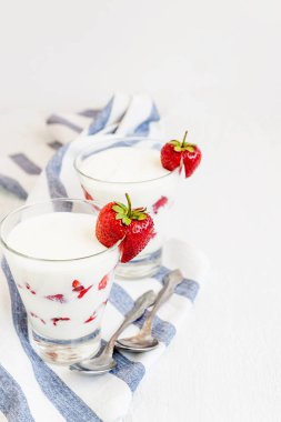 Tatlı yoğurt ve çilek katmanları bir cam üzerinde mavi bir şerit