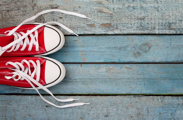 Mavi ahşap arka plan üzerinde gevşek örgüler ile kırmızı retro spor ayakkabı