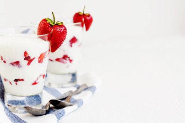 Tatlı yoğurt ve çilek katmanları bir cam üzerinde mavi bir şerit