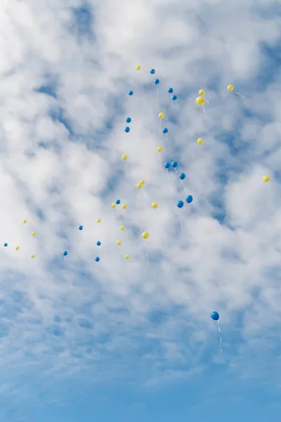 Les ballons multicolores volent dans un ciel bleu clair avec des nuages — Photo