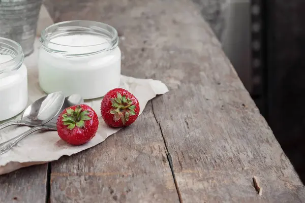 Yogur en un vaso y un cubo con fresas frescas en un cordón —  Fotos de Stock